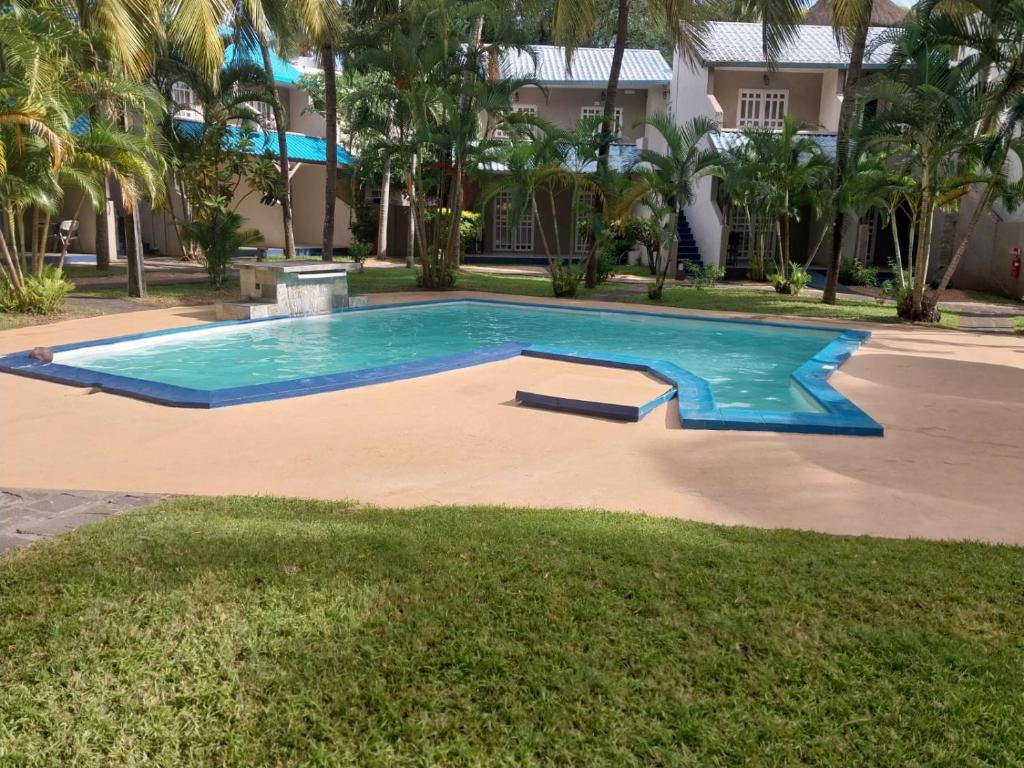 Peldbaseins ar skaidru ūdeni, ko ieskauj tropiskas palmas un zāli, radot relaksējošu atmosfēru. Apkārt esošās ēkas ir ar gaišām jumtu krāsām, kas papildina ainavu.