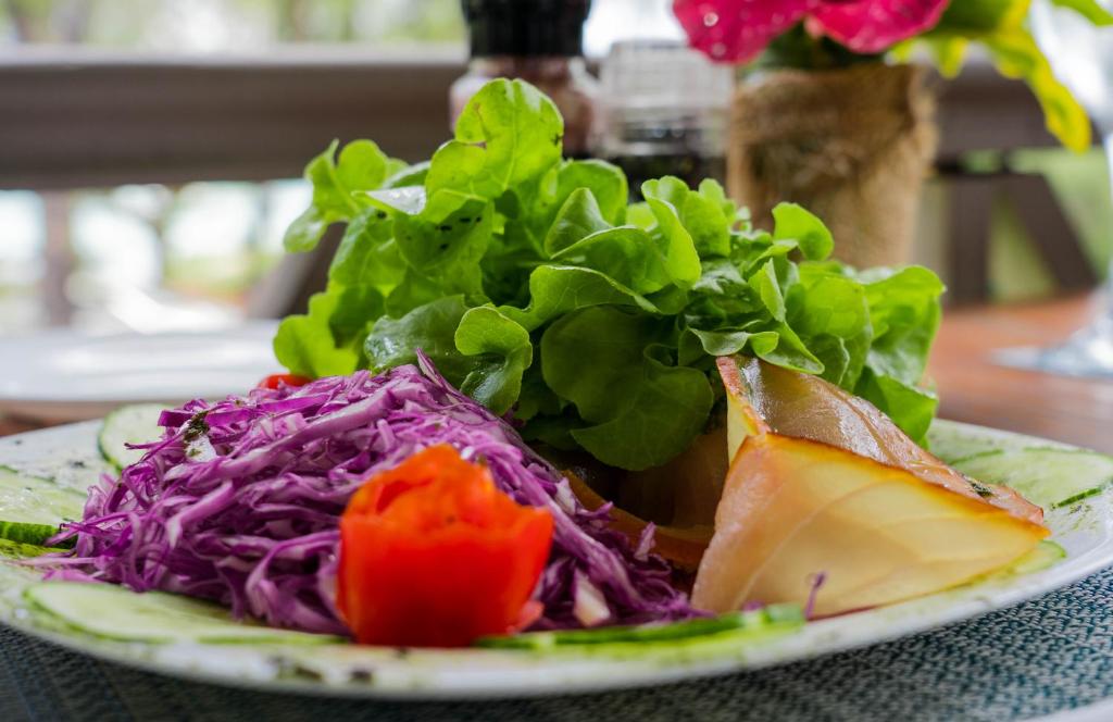 Svaiga salātu plate ar zilu kāpostu, tomātiem un zaļajiem lapu dārzeņiem, kas pasniegta restorānā.