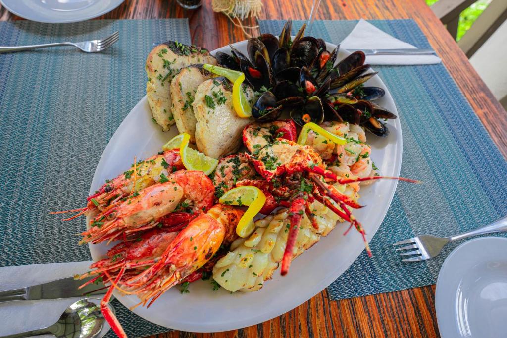 Jūras velšu plate ar garnelēm, omāriem un mīdijām, dekorēta ar citronu un zaļumiem, pasniegta uz koka galda.