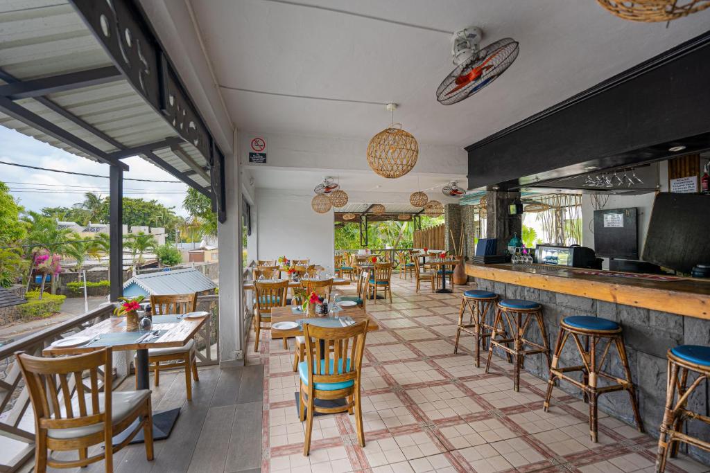 Restorāna iekšskats ar koka mēbelēm, elegantām interjera detaļām un panorāmas logiem, kas sniedz skatu uz dārzu. Piemērots vieta relaksējošām maltītēm.