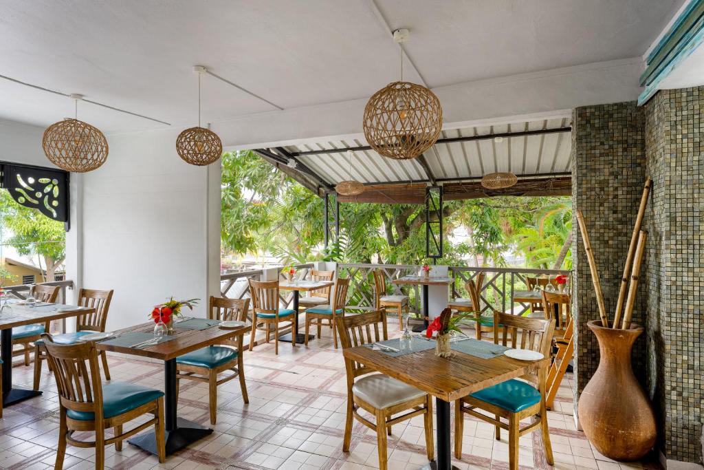 Mūsdienīgs restorāna interjers ar koka galdiem un krēsliem, rotātiem ar ziediem, un dabīgu apgaismojumu. Exotiska atmosfēra ar augiem un dekoratīvām lampām.