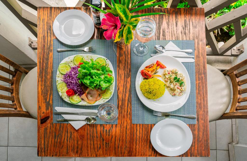 Svaiga un krāsaina maltīte, kas sastāv no dārzeņu salātiem un zivs ēdiena ar rīsiem, pasniegta uz eleganta galda ar dabīgiem elementiem.