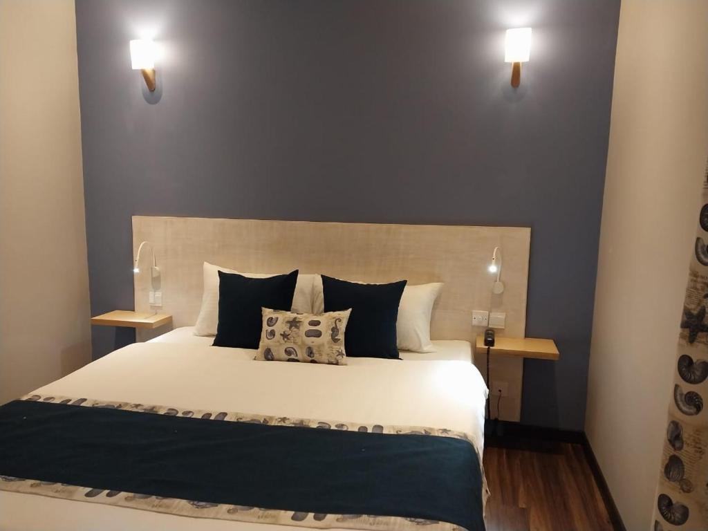 Mūsdienīga guļamistaba ar ērtu gultu, dekoratīviem spilveniem un siltu apgaismojumu. Sienas ir krāsotas pelēkā tonī, radot relaksējošu atmosfēru.