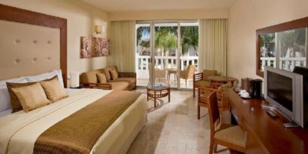 Mūsdienīga viesnīcas numura iekārtojums ar plašu gultu, atpūtas zonu un balkonu, kas nodrošina piekļuvi ārējai terasei. Interjers ir gaišs un viesmīlīgs, radot relaksētu atmosfēru.