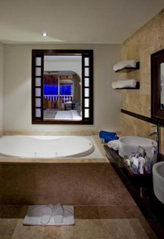 Mūsdienīgs vannas istabas interjers ar apaļu vannu, divām izlietnēm un logu, kas sniedz skatu uz ārpusi. Iekārtojums ir elegants un patīkams.