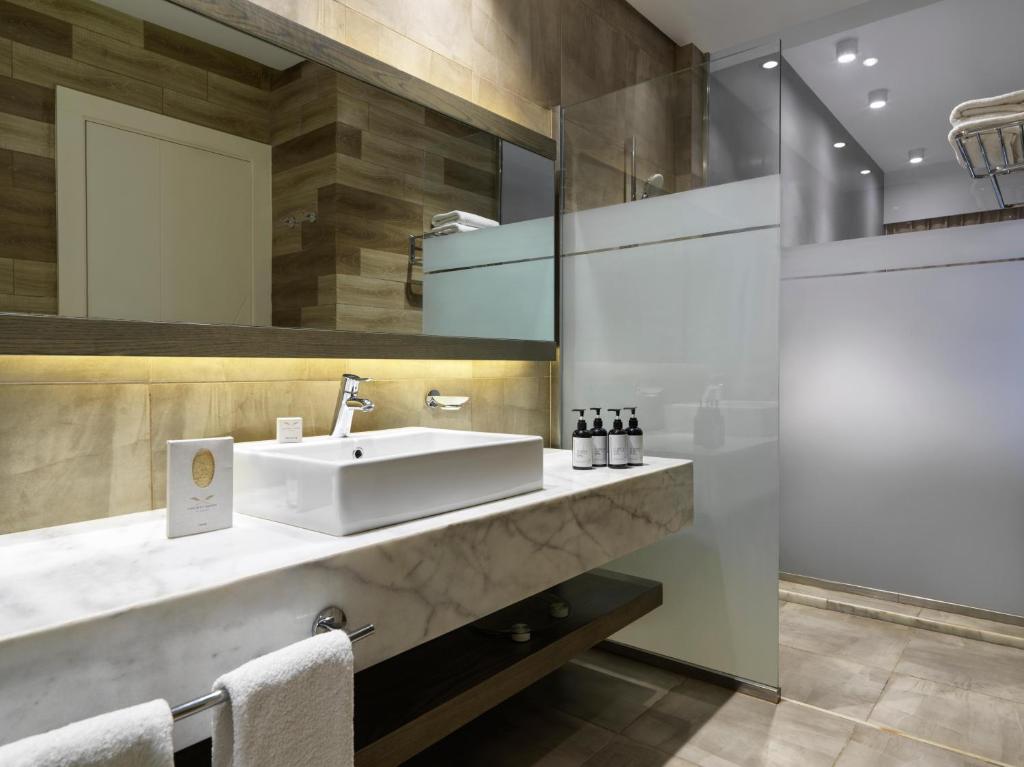 Mūsdienīgs vannas istabas interjers ar marmora izlietni un stikla dušu, kas papildināta ar elegantiem higiēnas līdzekļiem. Stilīgs apgaismojums un neitrālas krāsas rada relaksējošu atmosfēru.