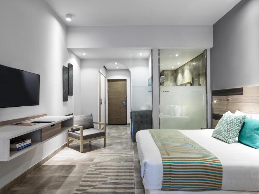 Mūsdienīgs viesnīcas numurs ar ērtu gultu, televizoru un sēžamo stūrīti. Numurā ir gaišas krāsas un eleganta apdare.