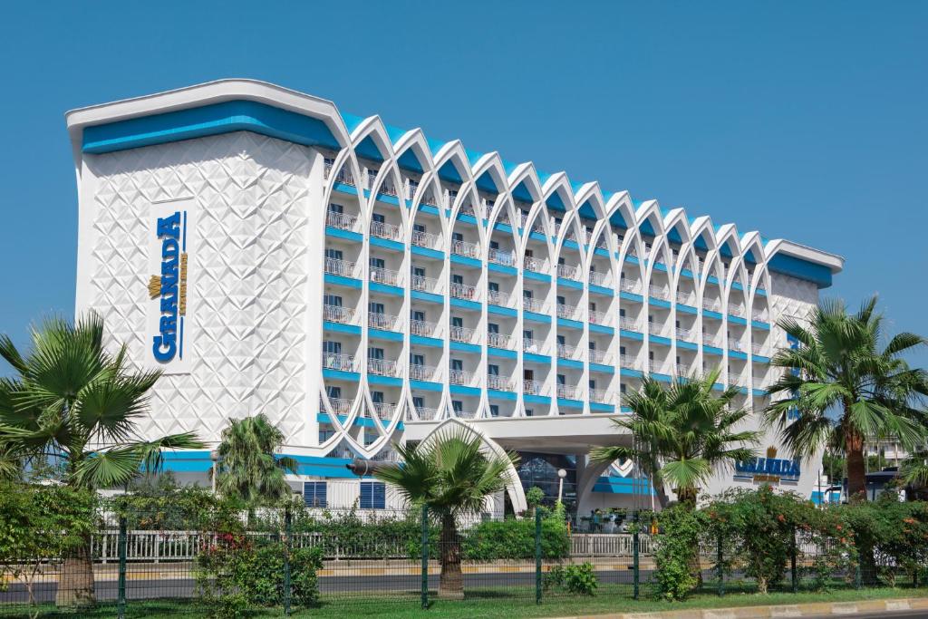 Moderns viesnīcas ēka ar unikālu arhitektūru un zilo fasādi, apkārtne ar palmām un zaļumiem.