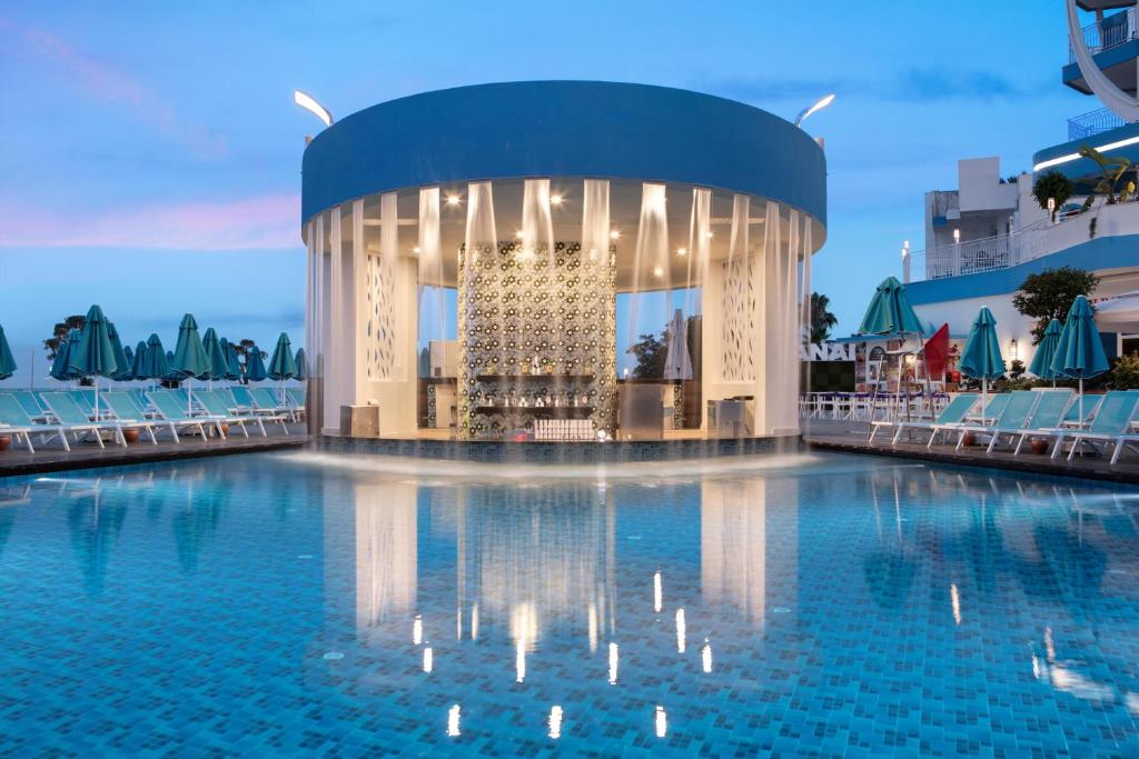 Mūsdienīgs baseins ar apaļu bāru centrā, ap kuru ir atpūtas krēsli un sauļošanās teltis. Ūdens virsma atspoguļo apkārtējo arhitektūru un debesu krāsas.