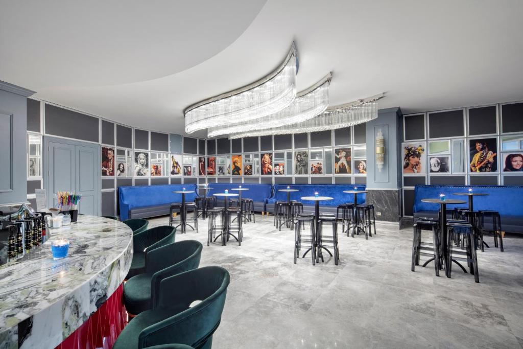 Mūsdienīgs bārs ar elegantām mēbelēm, elegantu apgaismojumu un mākslinieciskām fotogrāfijām uz sienām. Ideāla vieta relaksācijai un socializēšanai.
