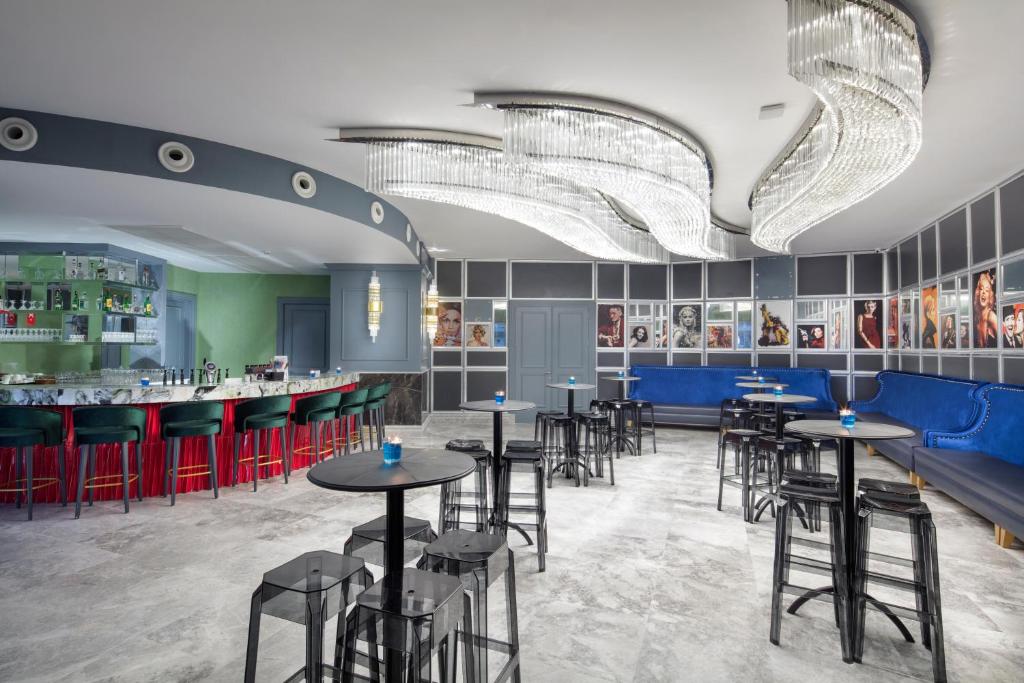 Mūsdienīgs bārs ar stilīgu interjeru, kurā ir krāsains apgaismojums un eleganti sēdvietas. Uz sienām redzami slaveni kinofilmu kadri.