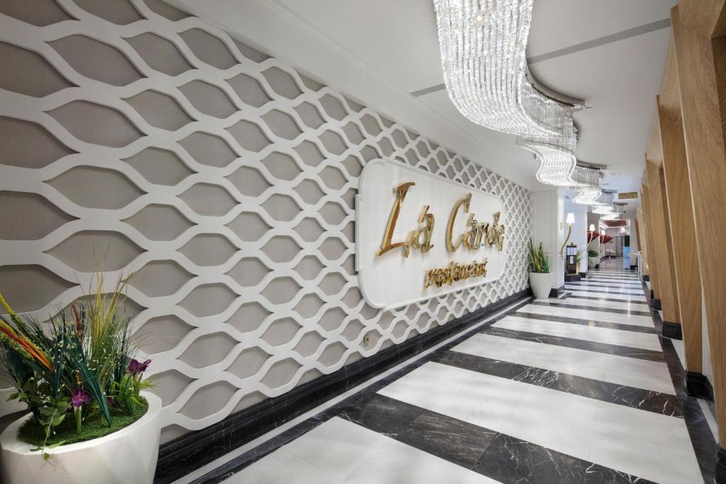 Mūsdienīgs restorāna "La Cantina" interjers ar elegantu sienu dizainu un greznu apgaismojumu. Ieejas koridors ar melnbaltu grīdu un dekoratīvām augu kompozīcijām.