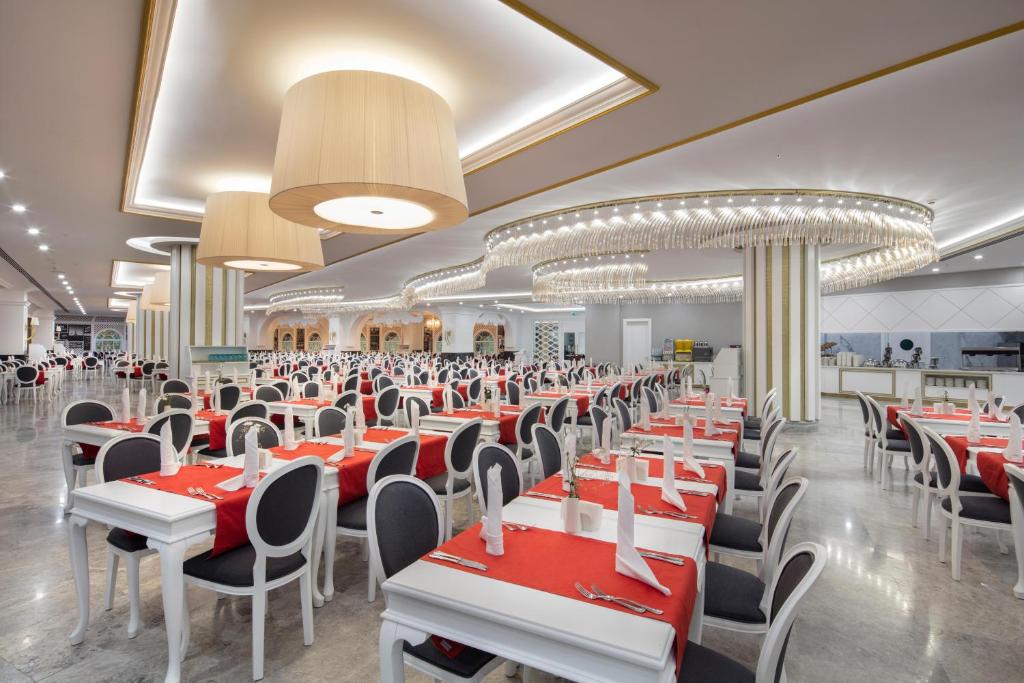 Lielas un elegantas restorāna telpas ar baltiem galdiem un sarkaniem galdautiem, kur sēž krēsli ar melniem un baltajiem akcentiem. Interjers rotāts ar modernām lampām un apgaismojumu, radot patīkamu atmosfēru.