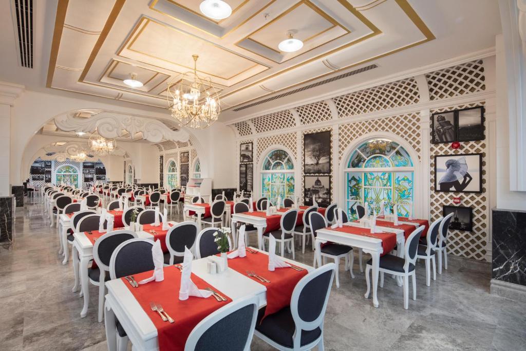 Eleganta restorāna interjers ar baltām galdiem un melniem krēsliem, dekorēts ar sarkaniem galdautiem un vitrāžām. Plaša telpa ar izsmalcinātu apgaismojumu un mākslas darbiem uz sienām.