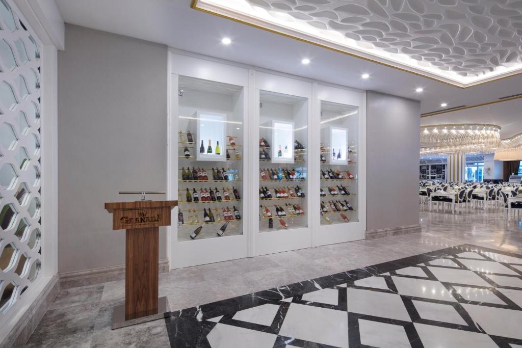 Mūsdienīgs restorāna interjers ar vīna izlasi stikla vitrīnā un elegantu koka stendu. Svaiga un gaiša atmosfēra ar izsmalcinātiem galdiem.