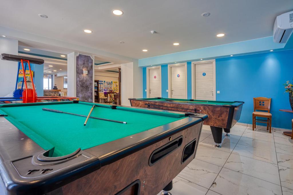 Billiards room ar zaļo galdu un mūsdienīgu interjeru, kurā redzami vairāki biljarda galdi un krēsli. Telpā ir gaiša apgaismojuma un krāsainas sienas, kas rada patīkamu atmosfēru.