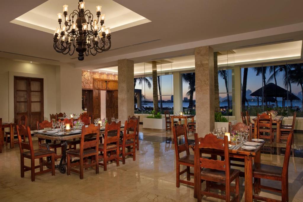 Elegants restorāns ar koka galds un krēsliem, apgaismots ar greznu lustru, piedāvā skatu uz pludmali un saulrietu. Interjers ir moderns un mājīgs, radot patīkamu atmosfēru.