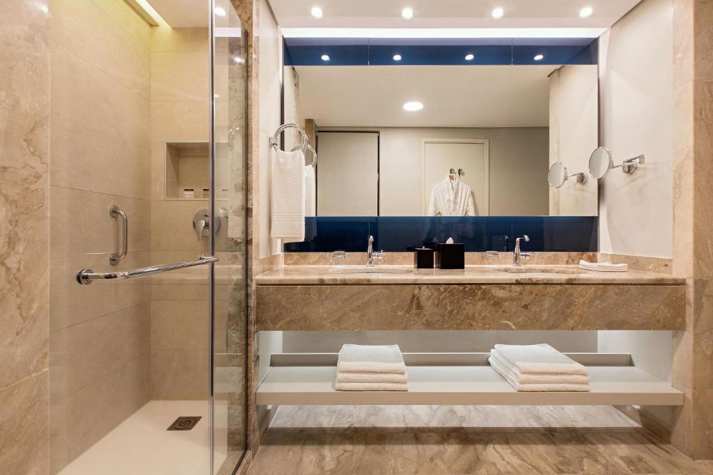 Mūsdienīga vannas istaba Sheraton Rhodes Resort ar dušu un elegantu izkārtojumu.