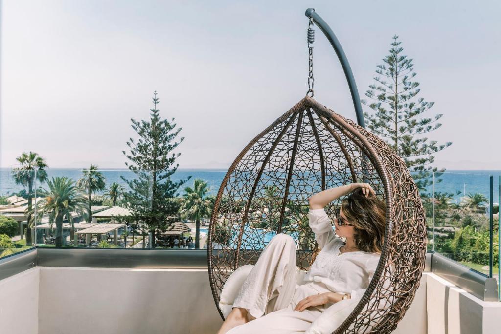 Sieviete atpūšas šūpuļtīklā pie Sheraton Rhodes Resort ar skatu uz piekrasti.