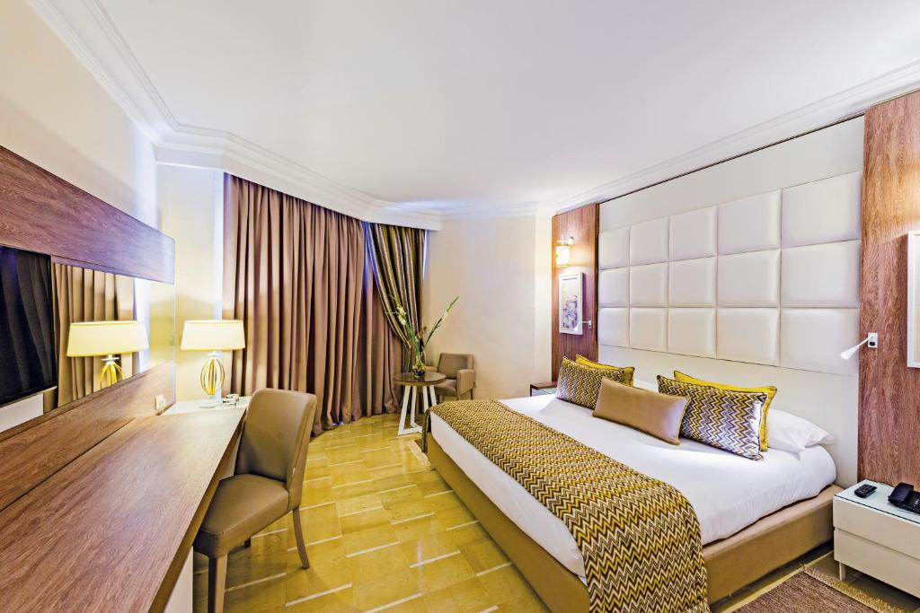 Mūsdienīgs viesnīcas numurs ar plašu gultu, elegantām interjera detaļām un dabiskiem gaismas avotiem. Numurā ir koka mēbeles, dzeltenas un brūnas krāsas akcenti un grezns apgaismojums.