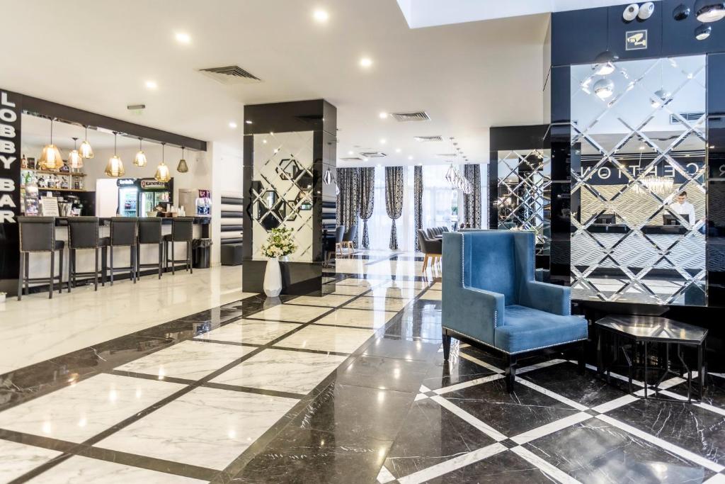 Mūsdienīga viesnīcas recepcija ar elegantu interjeru, ietverot bāru un atpūtas zonas. Grīda ir veidota ar melnbaltu mozaīku, bet telpu rotā stilīgas gaismas un logu aizkari.