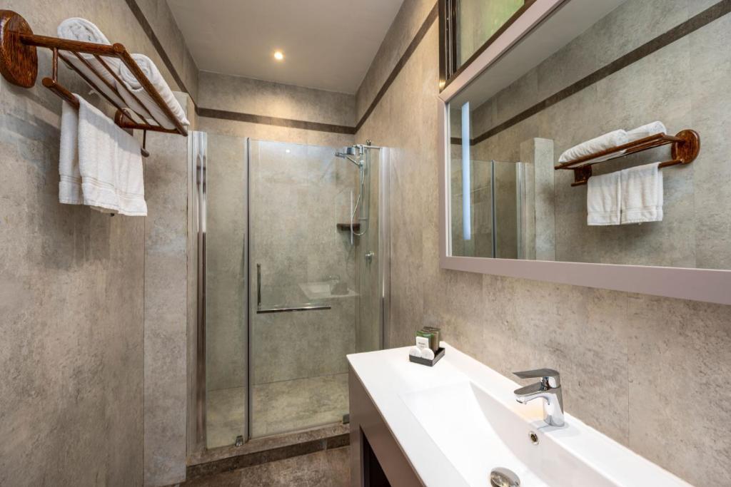 Moderns vannas istabas interjers ar dušu, baltiem dvieļiem un minimālistisku izskatu. Gaišas krāsas un elegants dizains rada relaksējošu atmosfēru.