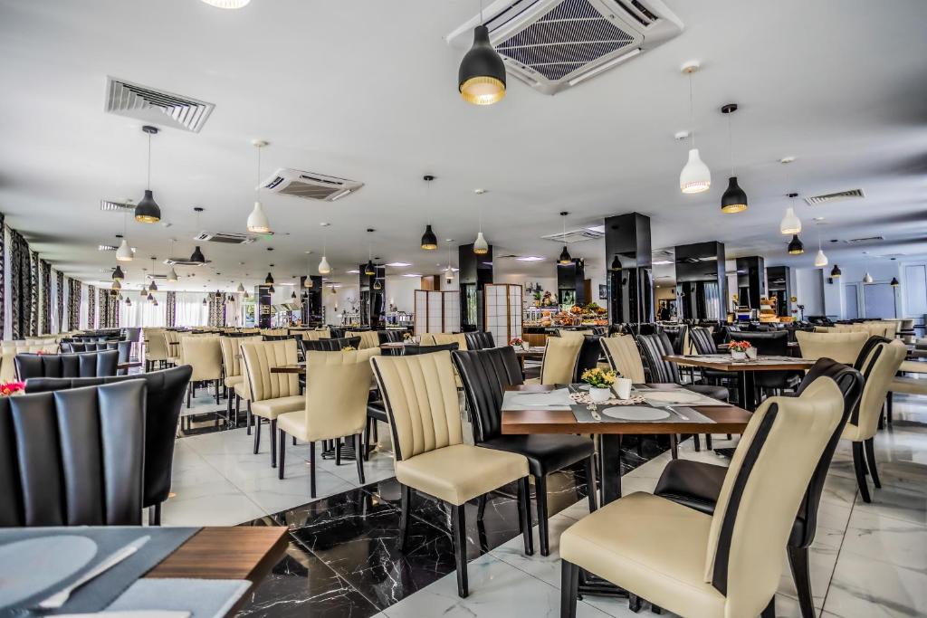 Mūsdienīgs restorāna iekārtojums ar elegantiem galdiem un krēsliem, kas piedāvā patīkamu atmosfēru ēšanai. Telpa ir gaiša un plaša, ar mūsdienīgu apgaismojumu un dekorācijām.