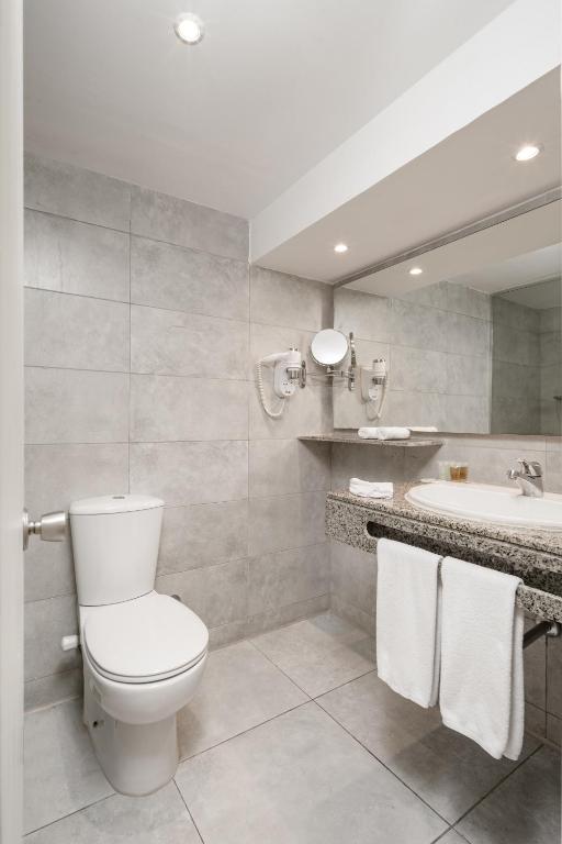 Mūsdienīgs vannas istaba Sindbad Club ar pelēkām flīzēm un akmens izlietni.