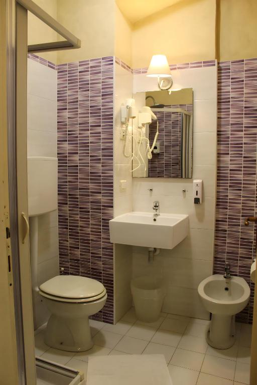 Mazu vannas istabu ar rozā flīzēm, dušas stūri un izlietni, kas ir aprīkota ar spoguli un higiēnas piederumiem.