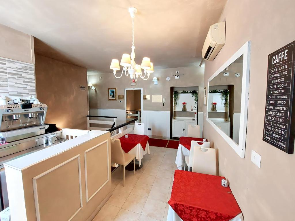 Kafejnīca ar elegantu interjeru, kurā redzami sarkani galdi un gaismas ķermenis. Interjers ir gaišs un moderns, ar kafejnīcas izvēlnes sarakstu pie sienas.