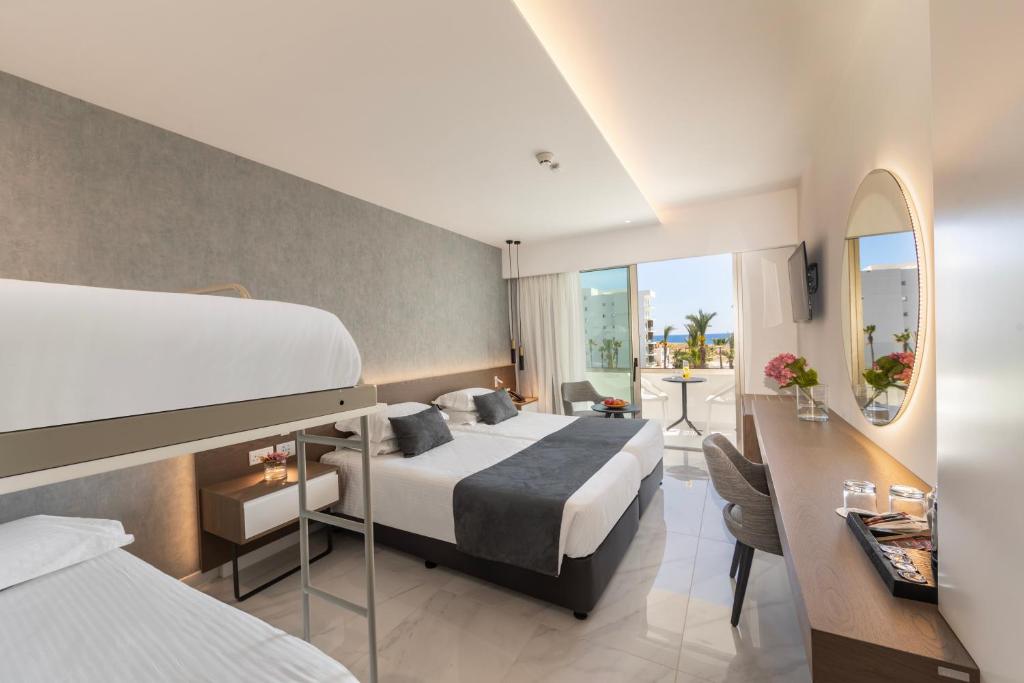 Mūsdienīgs viesnīcas numurs ar divām gultām un bērnu gultu, kā arī balkonu ar skatu uz jūru. Interjers ir gaišs un elegants, ar modernu mēbelējumu un dekoru.