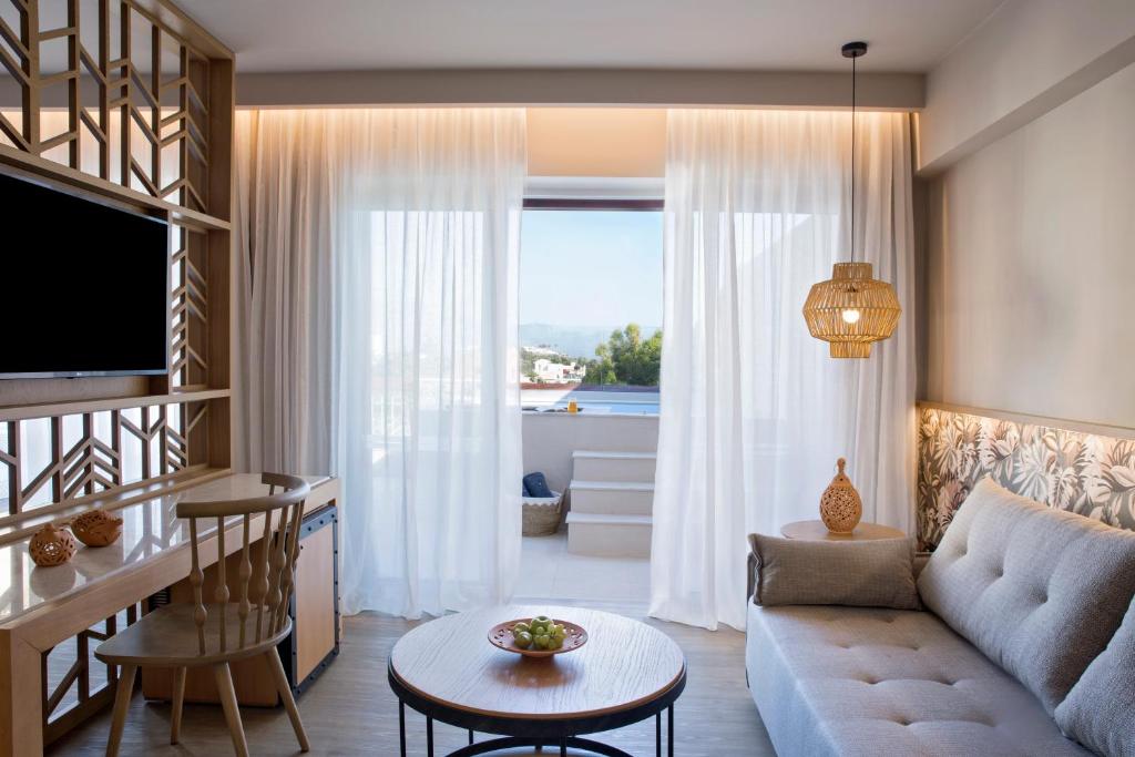 Mūsdienīgs interjers numurā Mirabello Bay Luxury Resort ar panorāmas logiem.