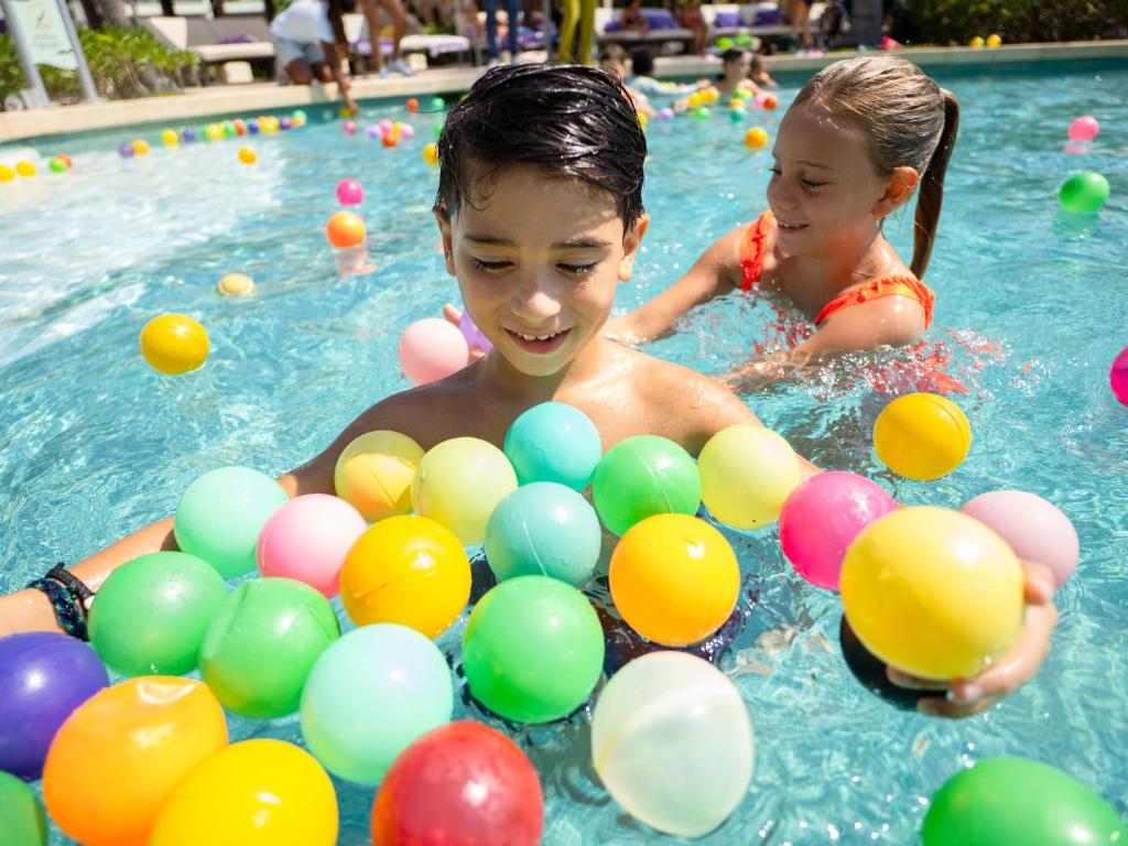 Bērni spēlējas ar krāsainām bumbiņām viesnīcas Paradisus Playa del Carmen baseinā.
