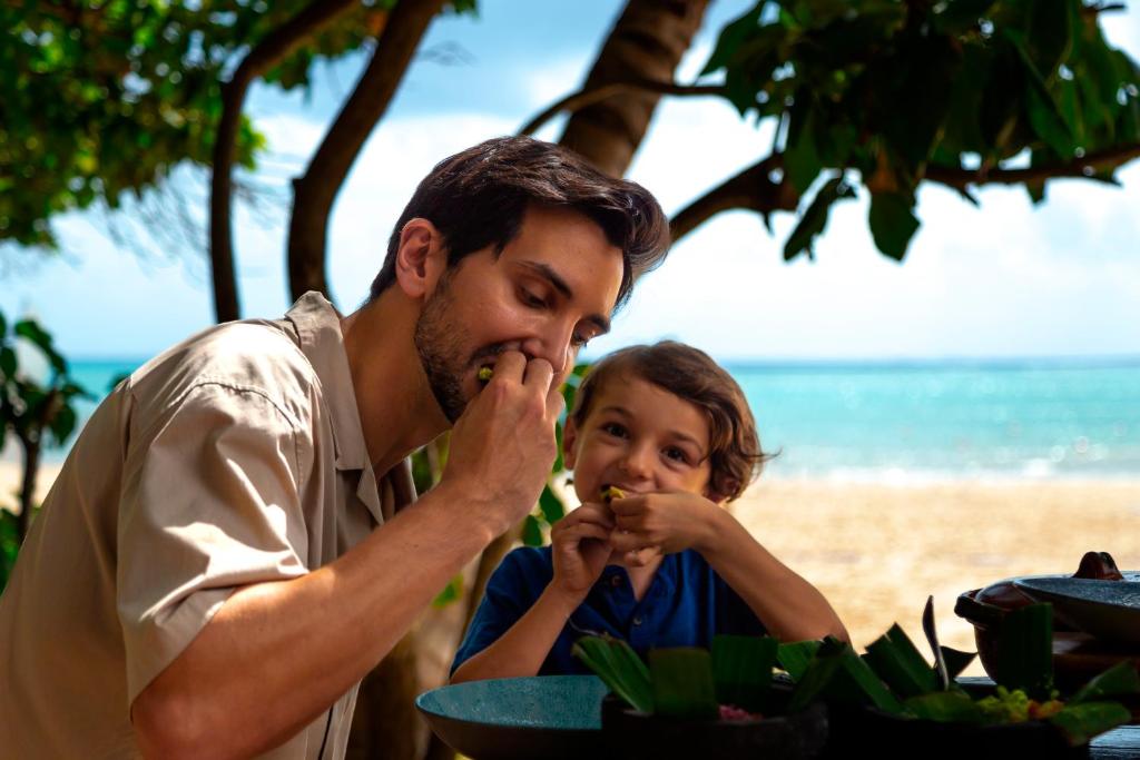 Vīrietis un bērns ēd kopā pie Paradisus Playa del Carmen pludmales.