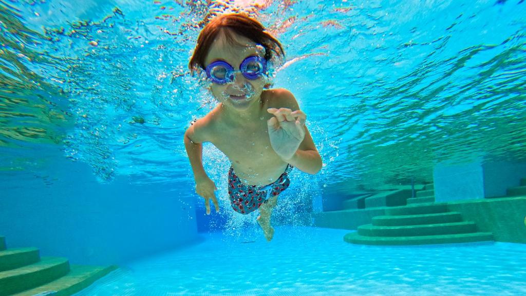 Bērns ar peldbrillēm, kas peld zem ūdens pie Paradisus Playa del Carmen.