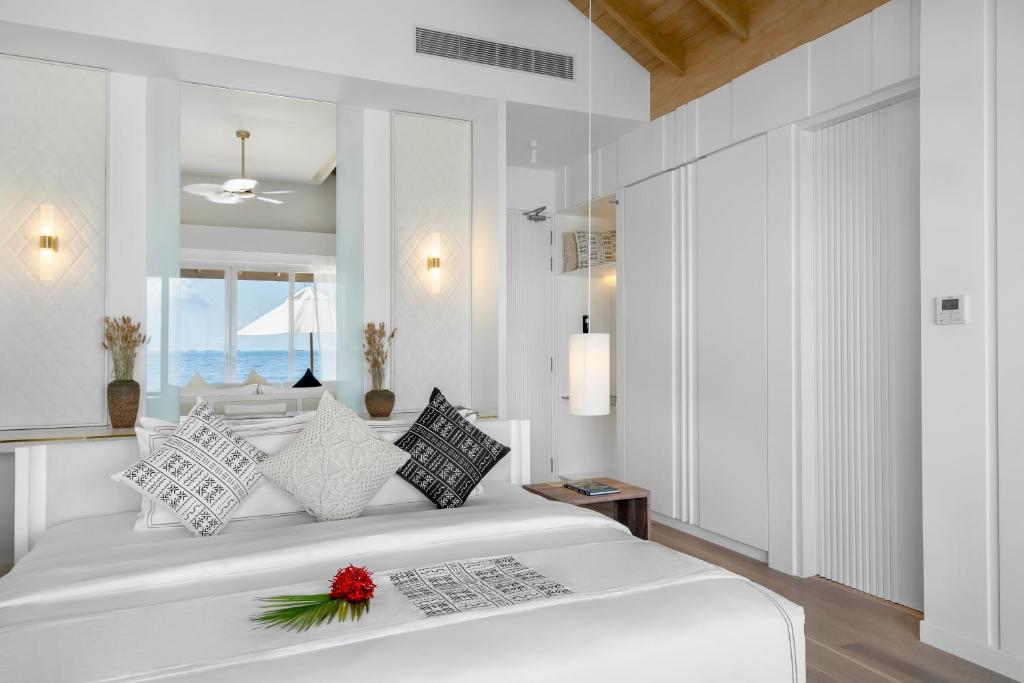 Moderns guļamistabas interjers ar piekrastes skatu, kurā ir eleganti spilveni un minimālistisks dizains. Logi atveras uz jūru, radot mierīgu atmosfēru.
