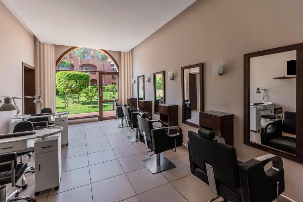 Skaistumkopšanas salons ar modernām frizieru krēsliem un spoguļiem, kas piedāvā skatu uz dārzu caur plašu logu. Gaiša un mājīga atmosfēra.