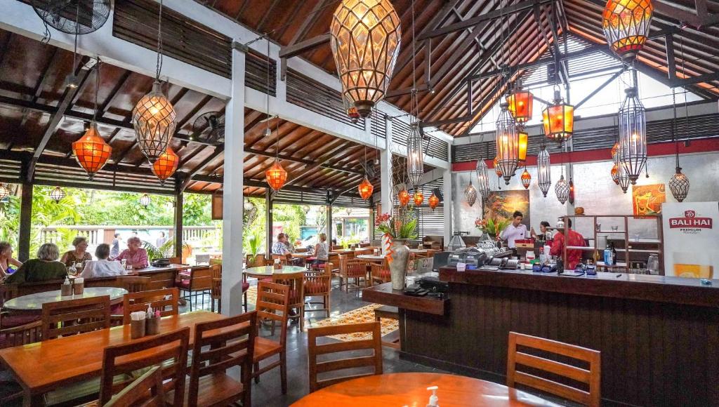Restorāna iekšpuse ar koka galdiem un krēsliem, siltu apgaismojumu un tropisku augu ainavu. Gaismas lukturi radīt patīkamu atmosfēru, piemēram, Bali stila interjeru.