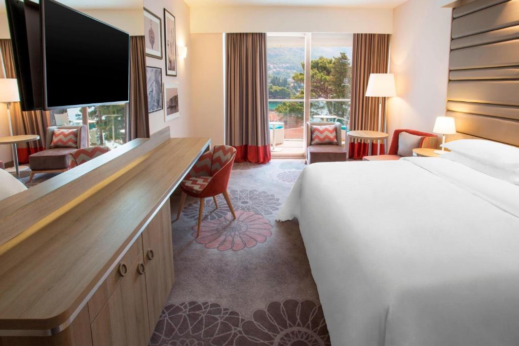 Moderns viesnīcas numurs ar plašu gultu, televizoru un ērtām mēbelēm, kas nodrošina relaksējošu atmosfēru. Logiem paveras skats uz dabu un terasi, radot patīkamu vidi.