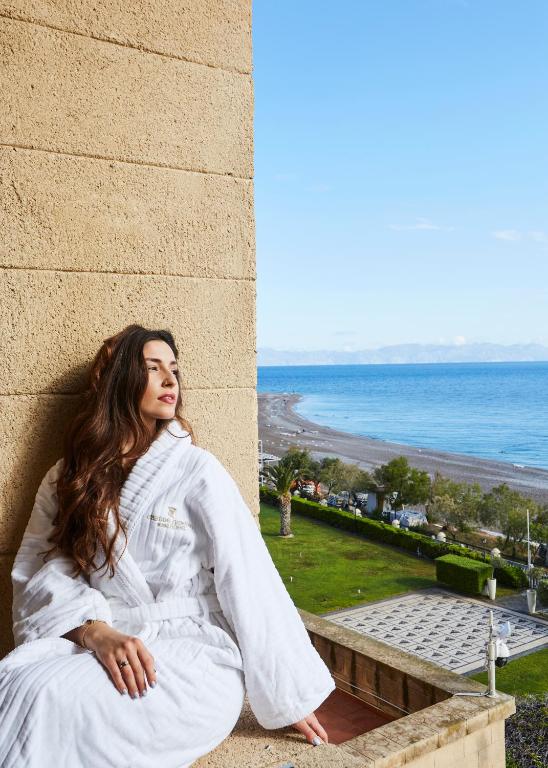 Sieviete baltā drānā ar skatu uz jūru pie viesnīcas Grande Albergo Delle Rose