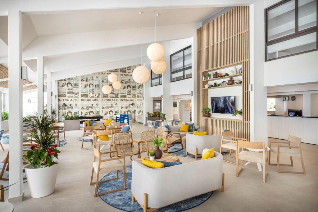 Mūsdienīgs viesnīcas ālāk, kas piedāvā gaišu un atvērtu interjeru ar ērtiem sēdekļiem, dekoratīvām gaismām un augu akcentiem, radot viesmīlīgu atmosfēru.