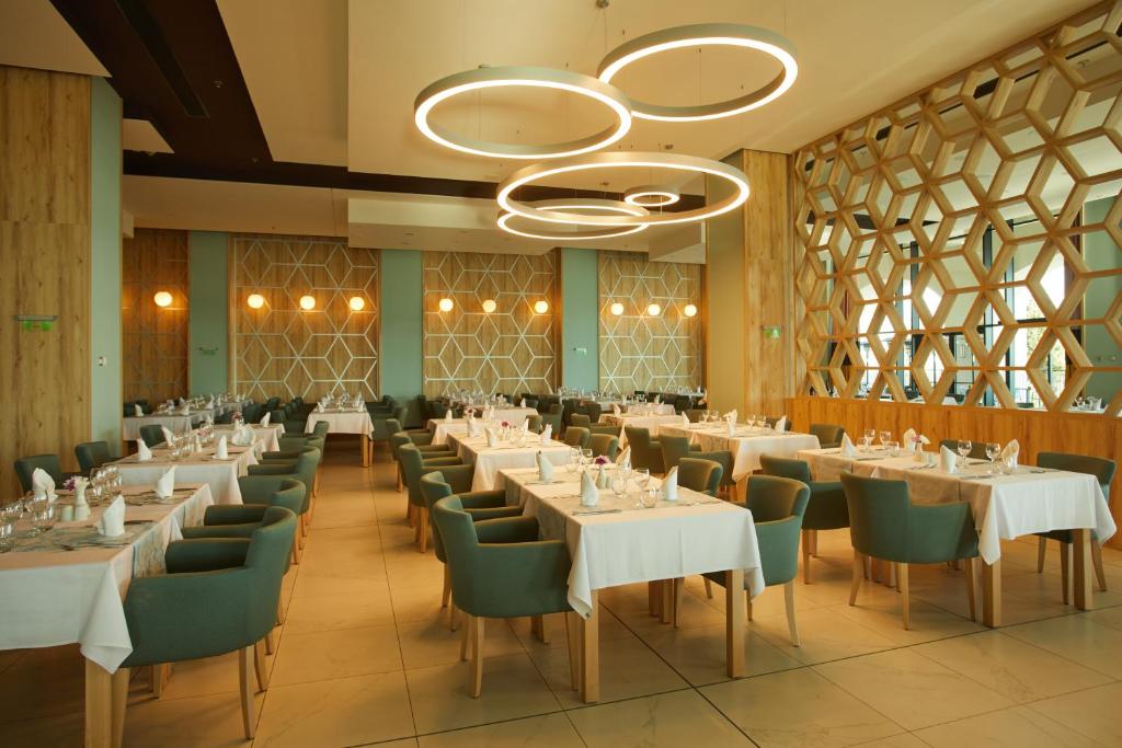 Mūsdienīgs restorāna interjers ar elegantiem galdiem un stilīgām gaismām, izceļot harmonisku atmosfēru un dizainu.