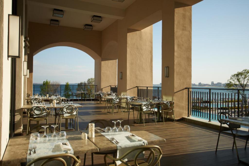 Terase ar skatu uz ūdeni, kur izkārtoti galdi un krēsli, piemērota ēdināšanai ārā. Gaisīgs un moderns interjers ar dabīgu apgaismojumu.