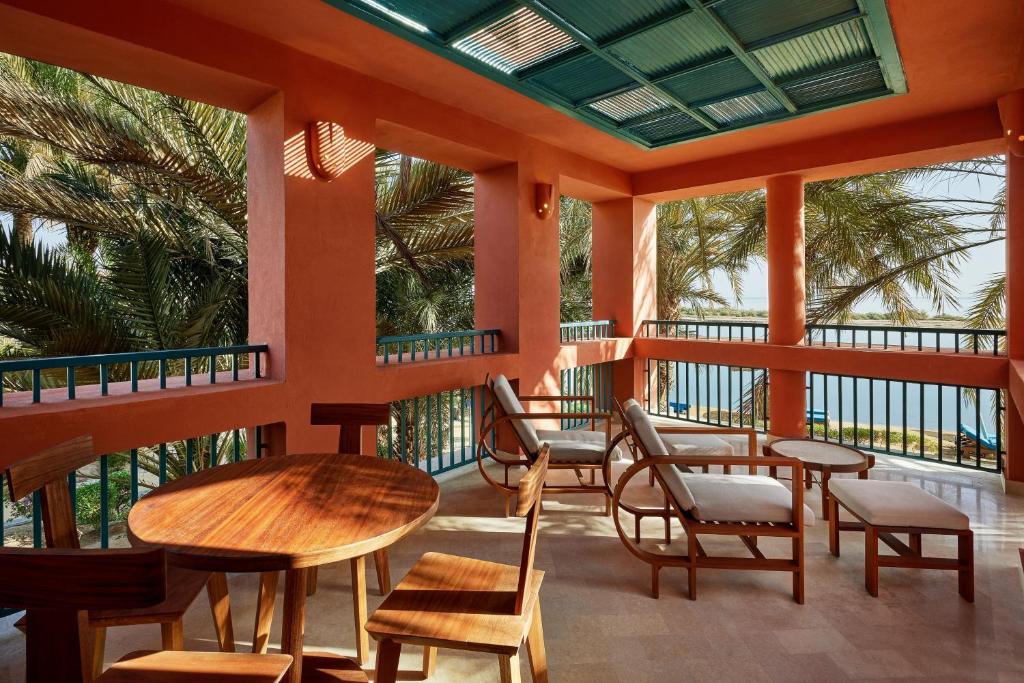 Terase ar koka mēbelēm pie Sheraton Miramar Resort, ar palmām fonā.