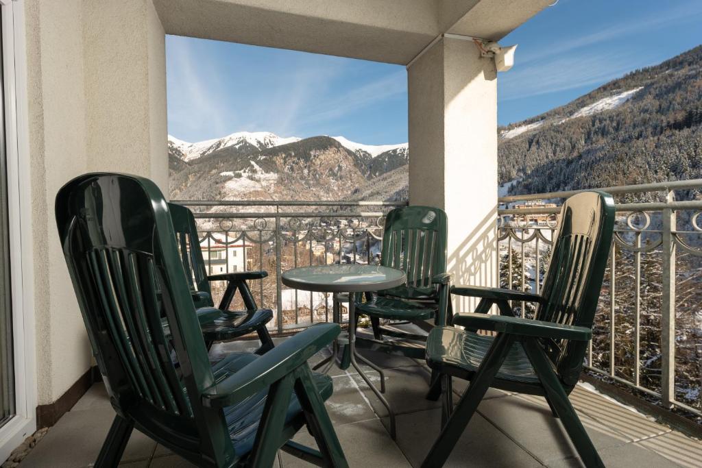 Balkons ar zaļām krēslām un galdu, no kura paveras skats uz kalniem un sniegu klātām ainavām. Ideāla vieta relaksācijai un dabas baudīšanai.