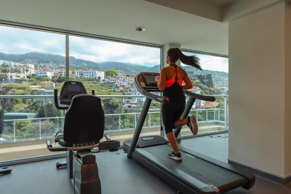 Sieviete skrien uz skrejceļa sporta zālē ar panorāmas skatu uz kalniem un pilsētu. 