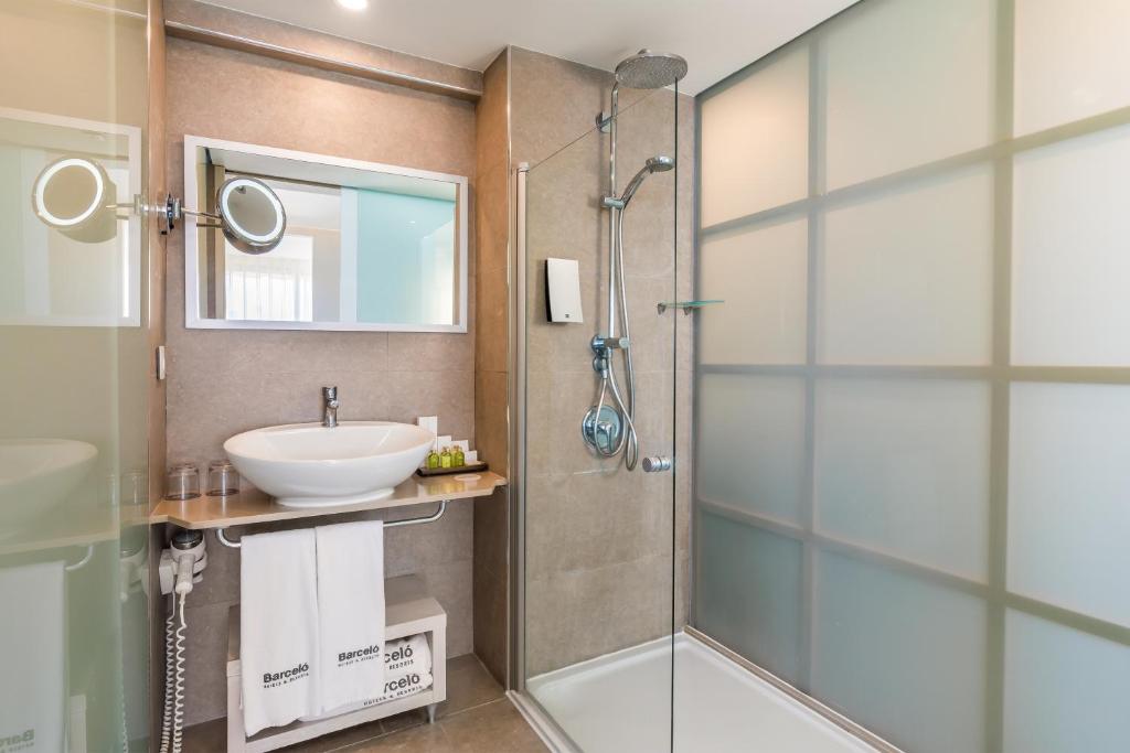 Mūsdienīga vannas istaba ar stikla dušu, modernu izskatu un elegantu izlietni. Vannas istabā ir arī spogulis un higiēnas piederumi.