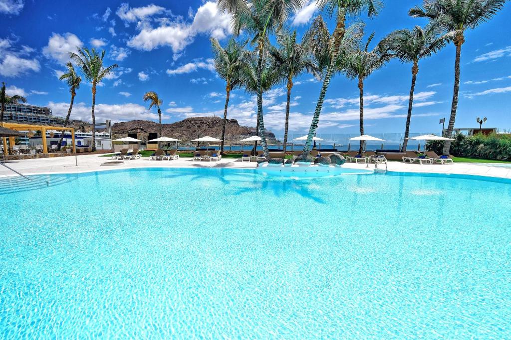 Lielisks baseins ar palmām un skaidru debesīm, radot relaksējošu atmosfēru. Ideāla vieta atpūtai un sauļošanās brīžiem.