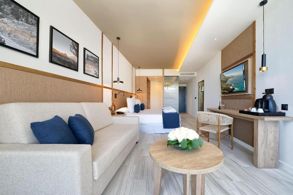 Mūsdienīgi iekārtots viesnīcas numurs ar dīvānu, koka galdu un televizoru, apvienojot komfortu un estētiku. Uz sienām ir melnbaltas fotogrāfijas, radot mājīgu atmosfēru.