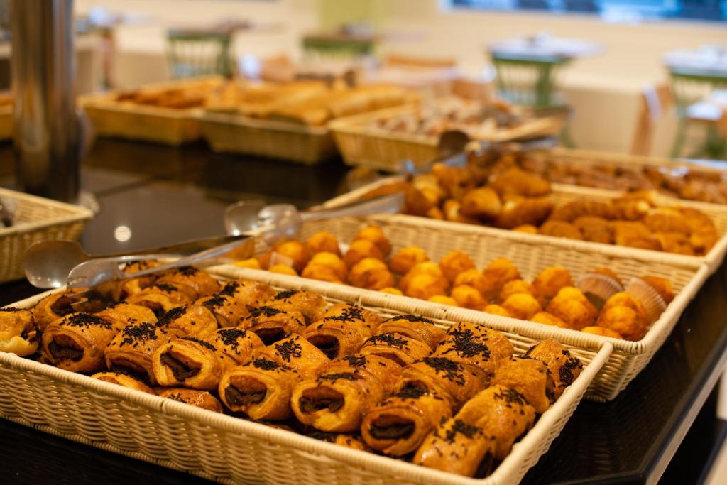 Piknika galda klāšana ar dažādām konditorejas izstrādājumiem, tostarp rullīšiem un maizītēm, kas izkārtoti grozos.